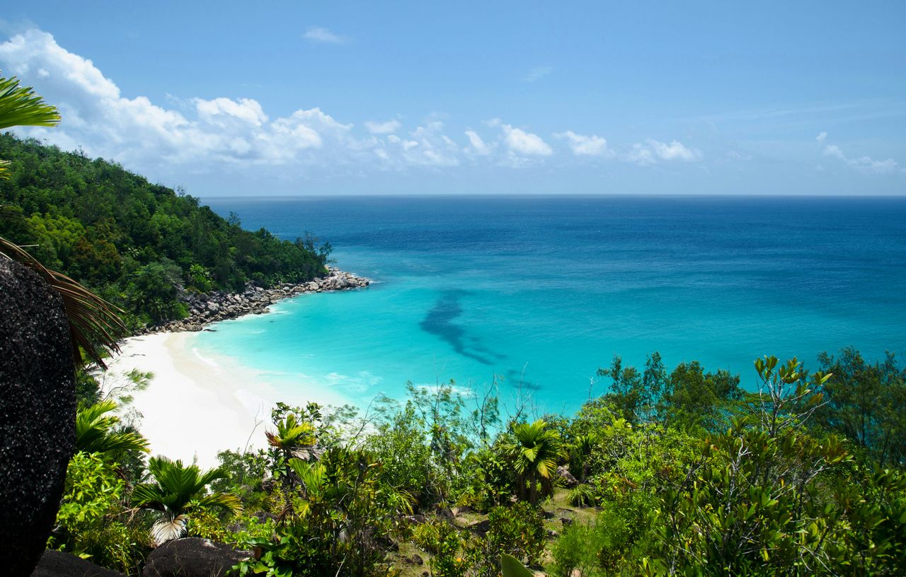 A tropical beach from above: turquoise water, white sand and green hills, edited by Maren.